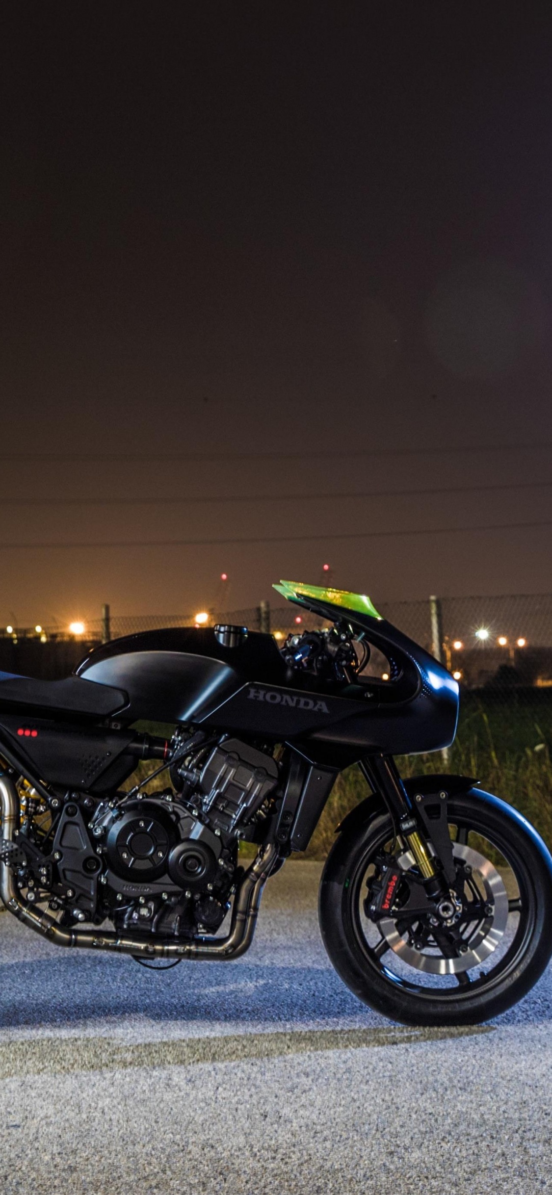 Schwarzes Und Grünes Sportfahrrad Auf Grauer Asphaltstraße Während Der Nachtzeit. Wallpaper in 1125x2436 Resolution