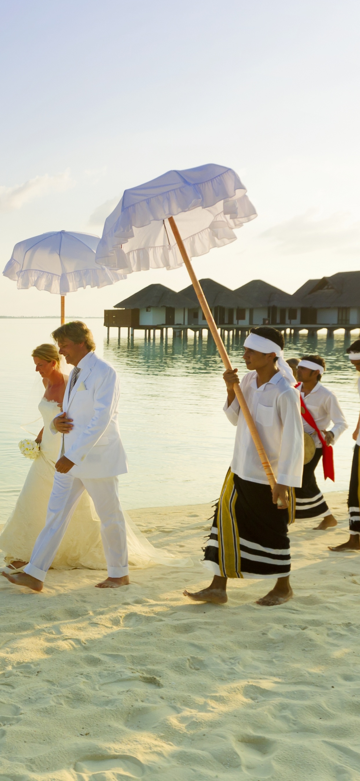 Woman in White Dress Holding Umbrella Walking on Beach During Daytime. Wallpaper in 1242x2688 Resolution