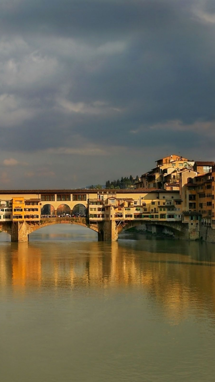 Edificio de Hormigón Marrón Cerca Del Río Bajo un Cielo Nublado Durante el Día. Wallpaper in 750x1334 Resolution
