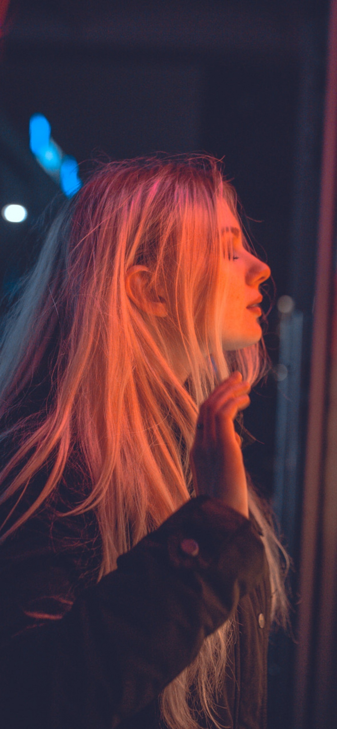 Frau im Schwarzen Langarmhemd, Die in Der Nähe Von Roten Und Gelben Neonlichtschildern Steht. Wallpaper in 1125x2436 Resolution