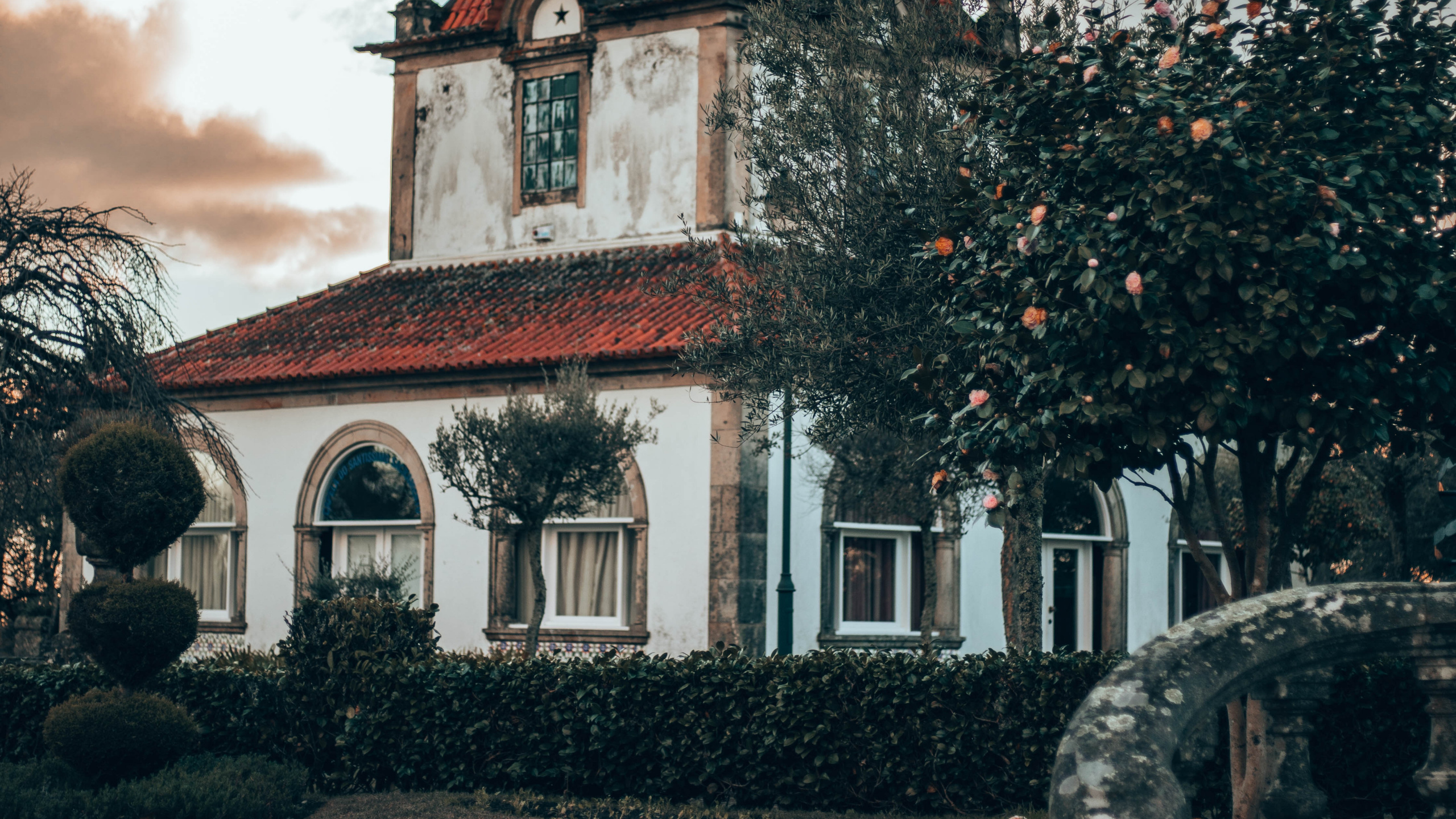 Red and White Concrete Building Near Green Trees Under White Clouds During Daytime. Wallpaper in 2560x1440 Resolution