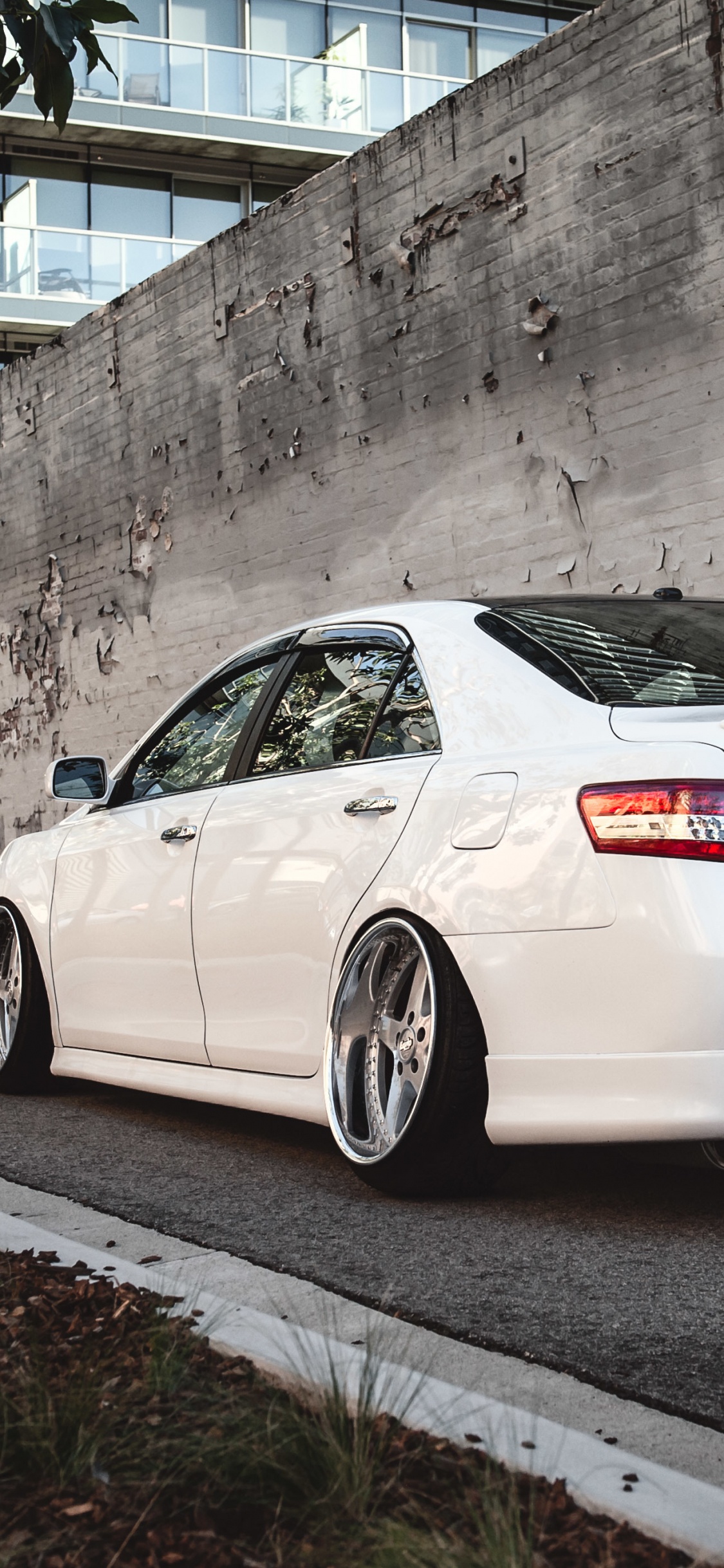 Weißer Porsche 911 Geparkt Neben Grauer Betonwand. Wallpaper in 1125x2436 Resolution