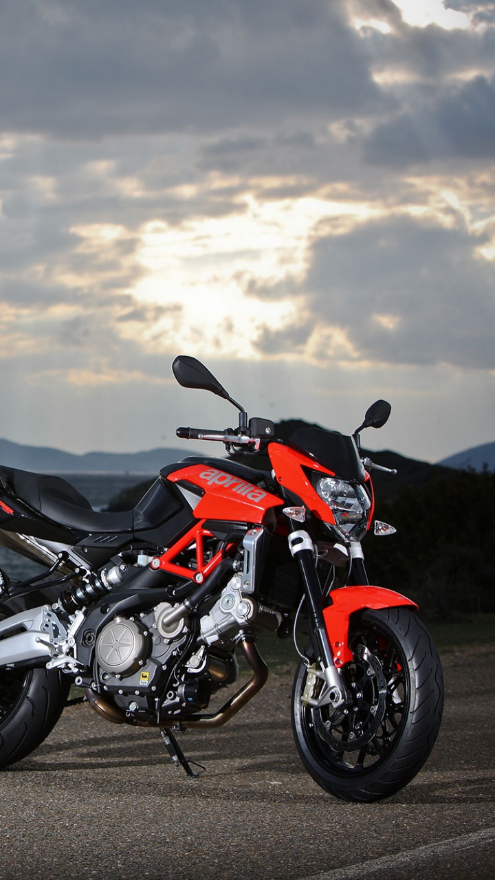 Black and Orange Sports Bike Parked on Gray Concrete Road Near Body of Water During Daytime. Wallpaper in 720x1280 Resolution