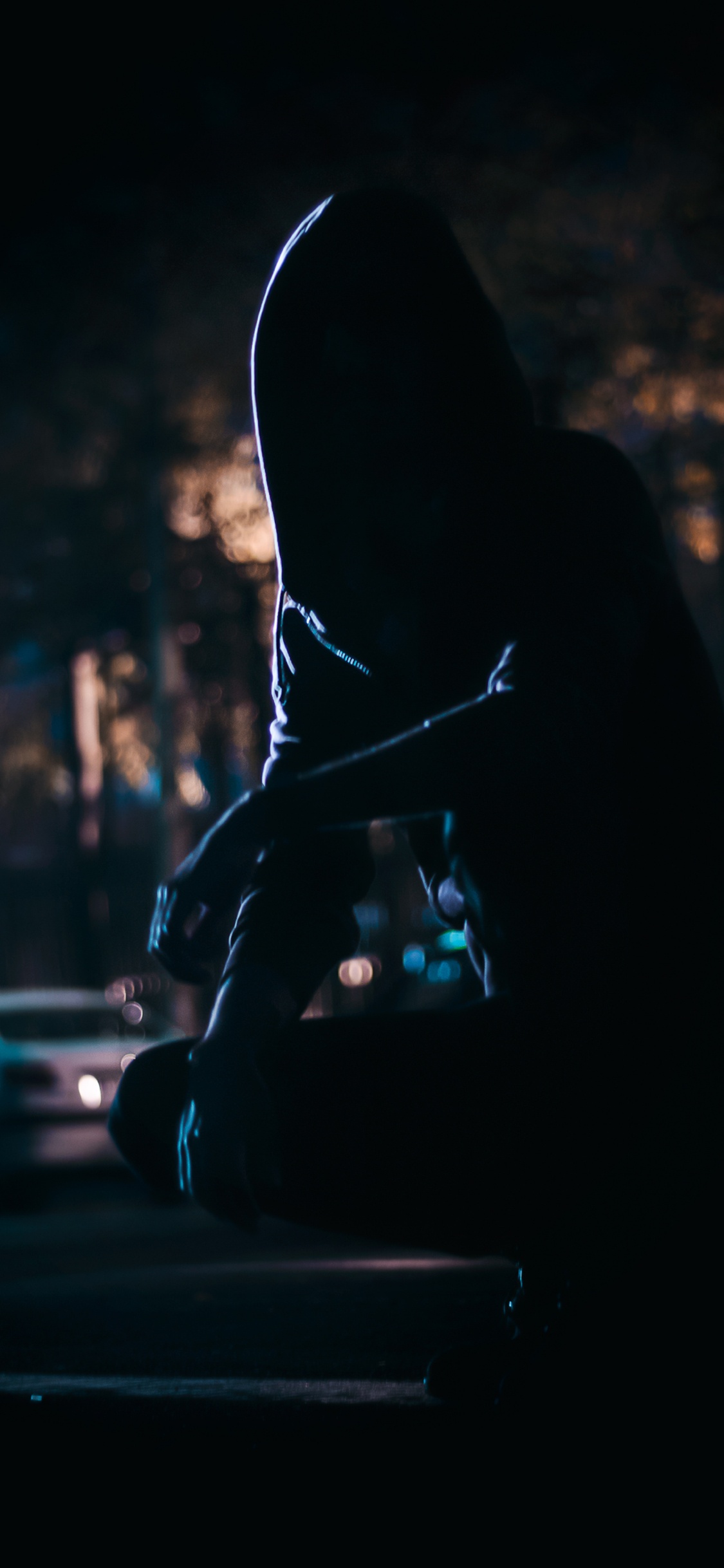 Silhouette of Person Sitting on The Street During Night Time. Wallpaper in 1125x2436 Resolution