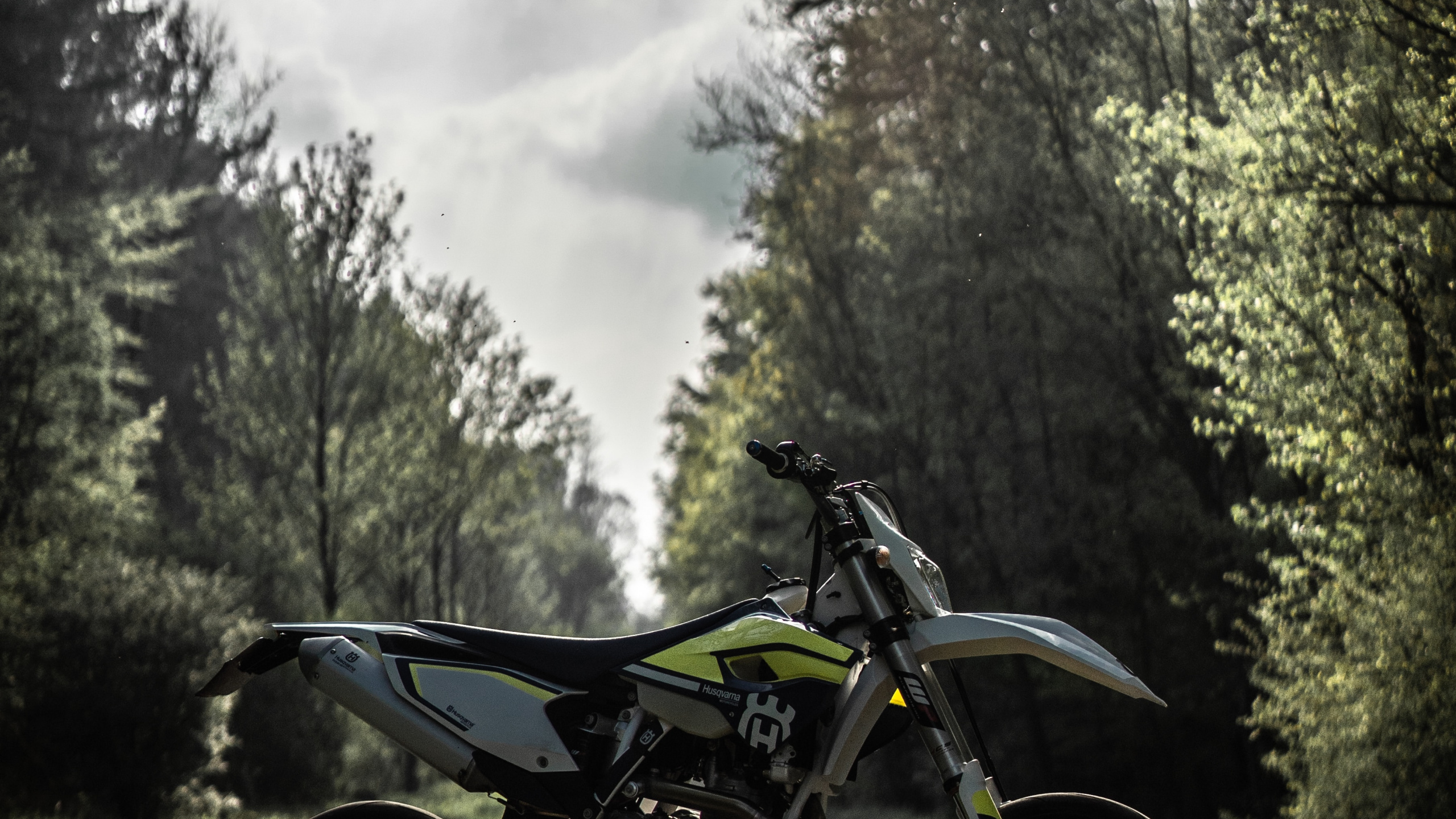 Black Motorcycle Parked on Dirt Road Near Green Trees During Daytime. Wallpaper in 2560x1440 Resolution