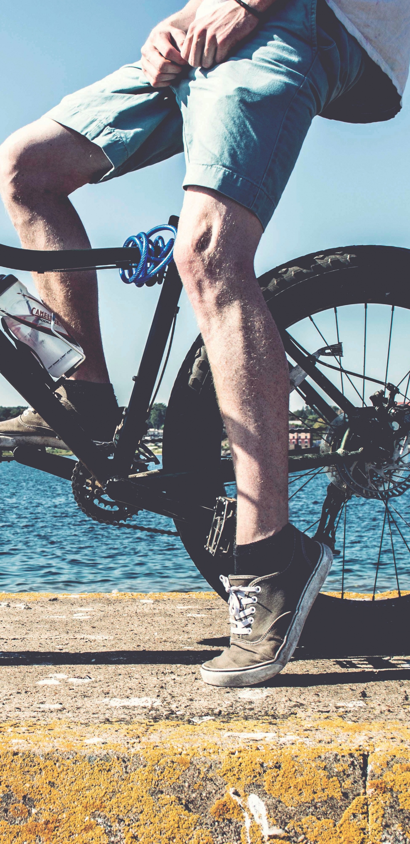Person in Blue Denim Jeans Riding Black Mountain Bike Near Body of Water During Daytime. Wallpaper in 1440x2960 Resolution