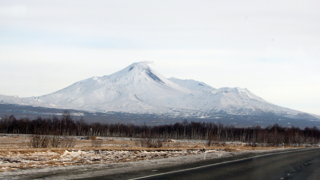 Gray Asphalt Road Near Brown Trees and Snow Covered Mountain During Daytime. Wallpaper in 1280x720 Resolution