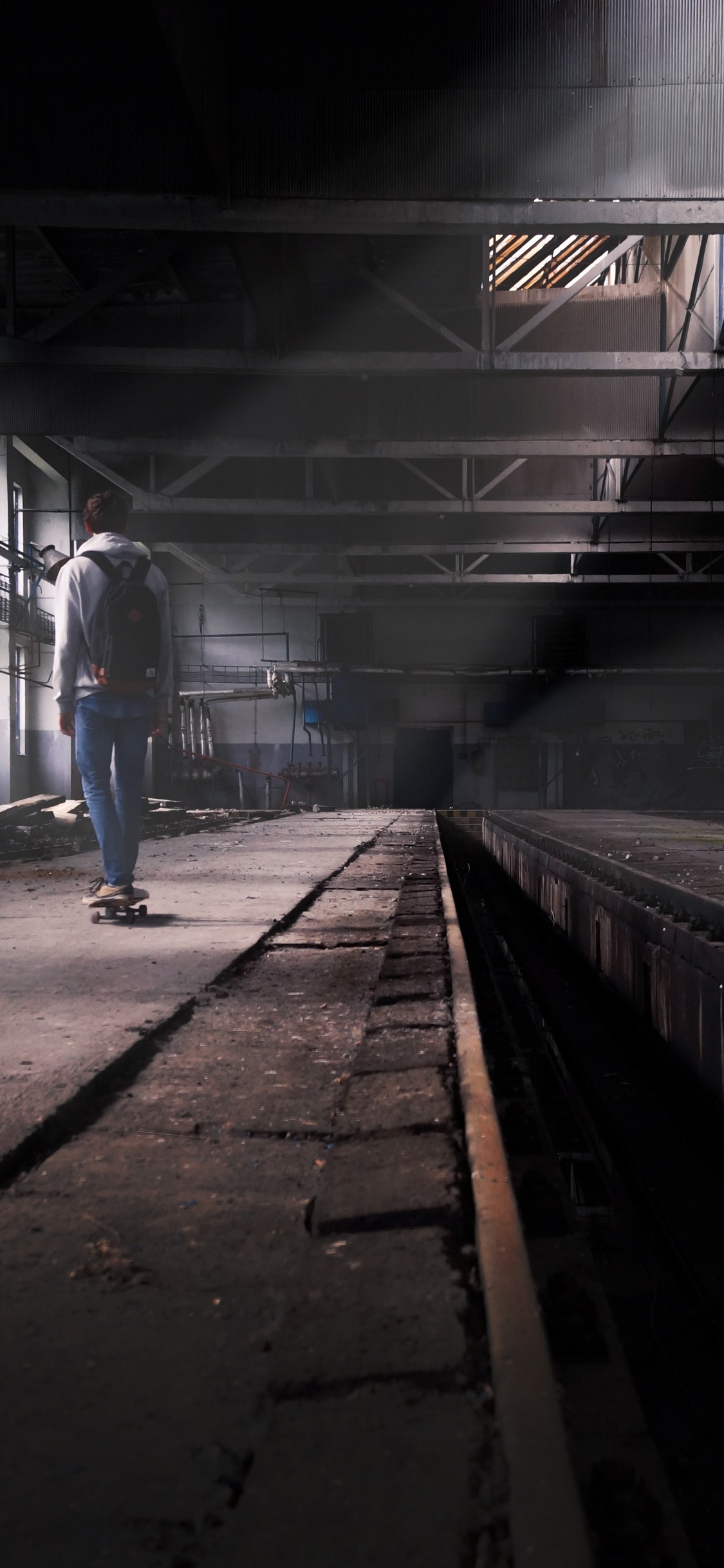 Man in Blue Denim Jeans Walking on Train Station. Wallpaper in 1125x2436 Resolution