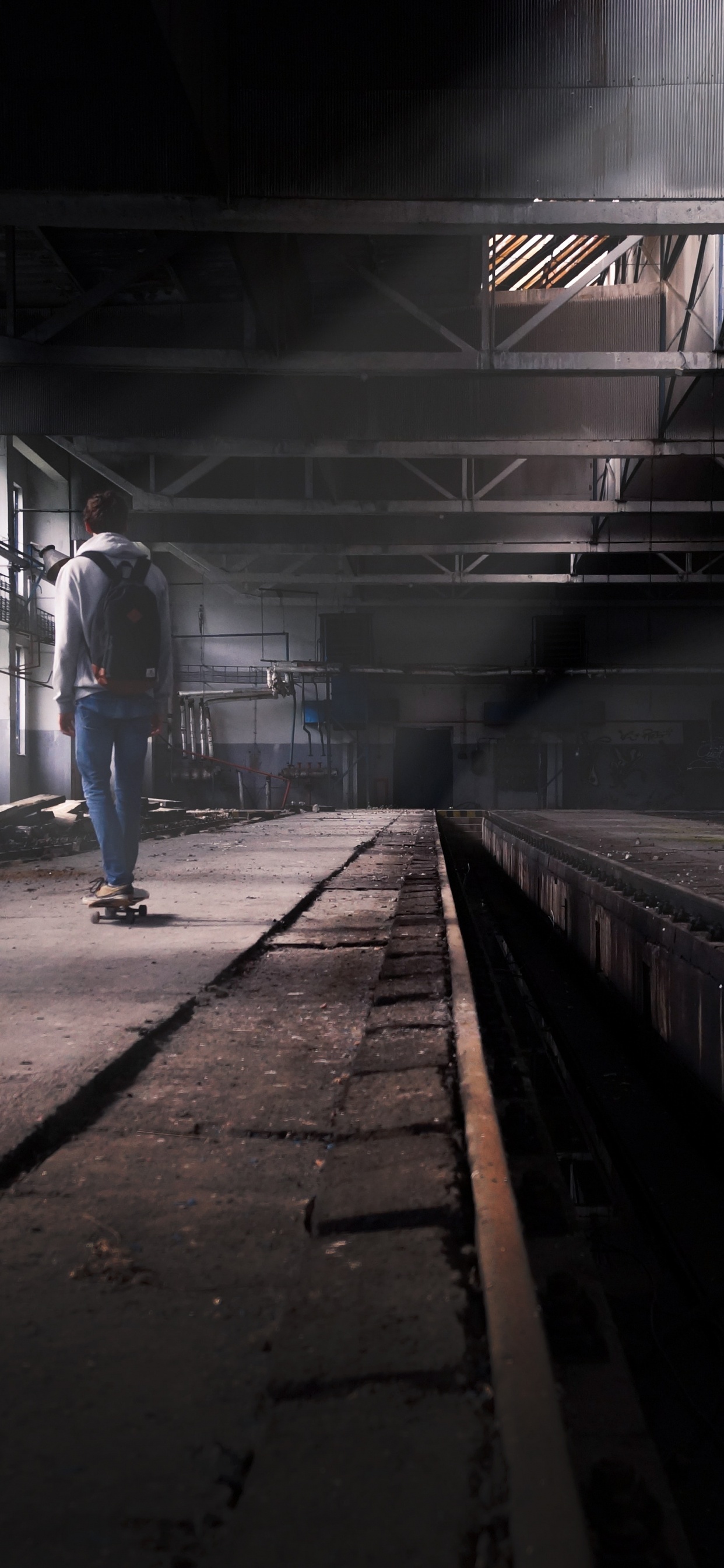 Man in Blue Denim Jeans Walking on Train Station. Wallpaper in 1242x2688 Resolution