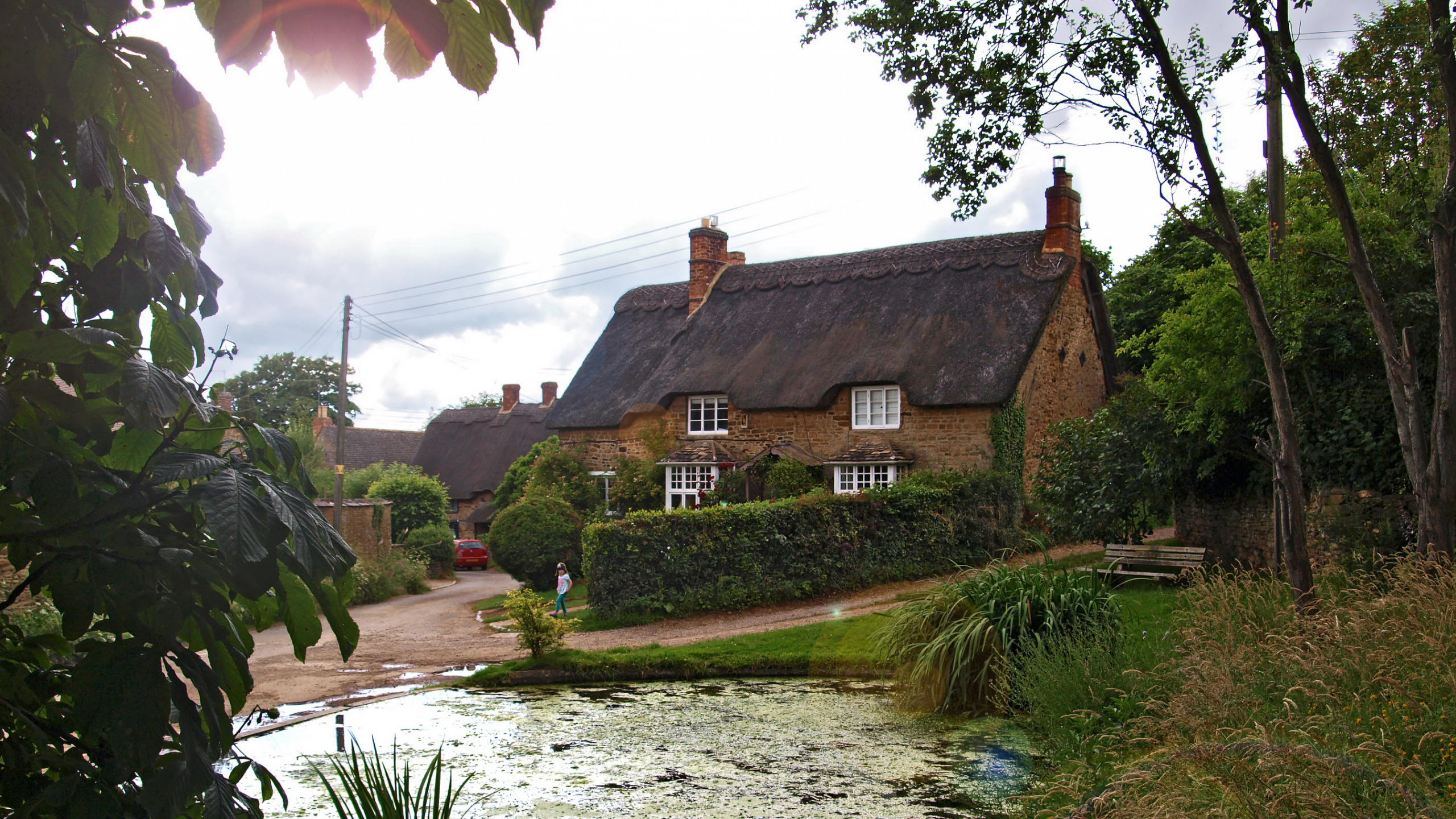 Brown and White House Near Green Trees and Body of Water During Daytime. Wallpaper in 2560x1440 Resolution