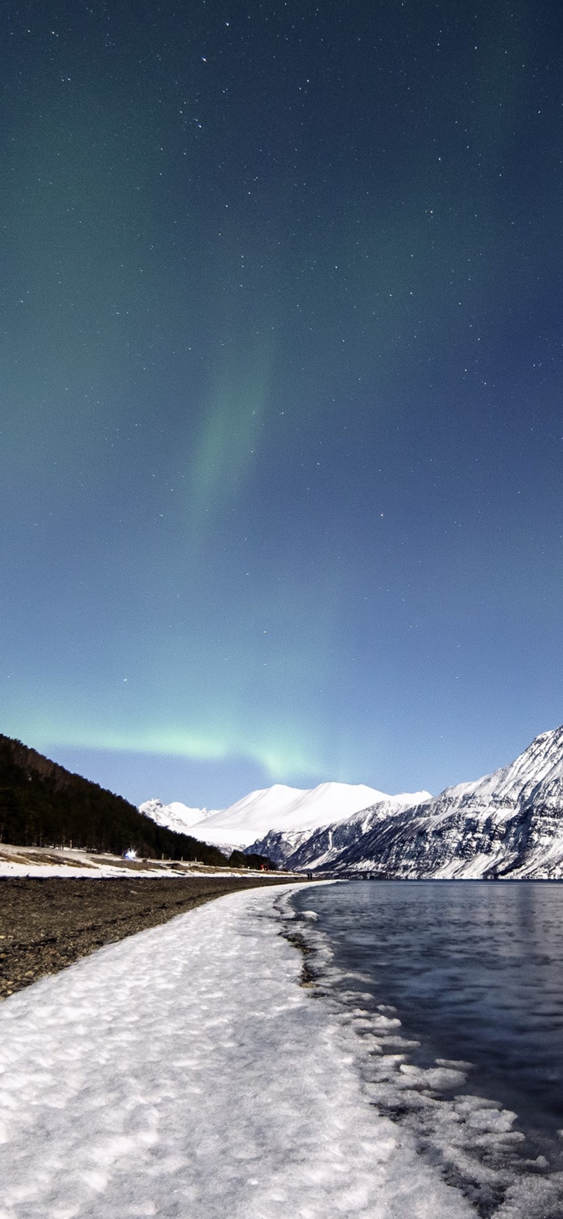 Montaña Cubierta de Nieve Cerca Del Cuerpo de Agua Durante la Noche. Wallpaper in 1125x2436 Resolution