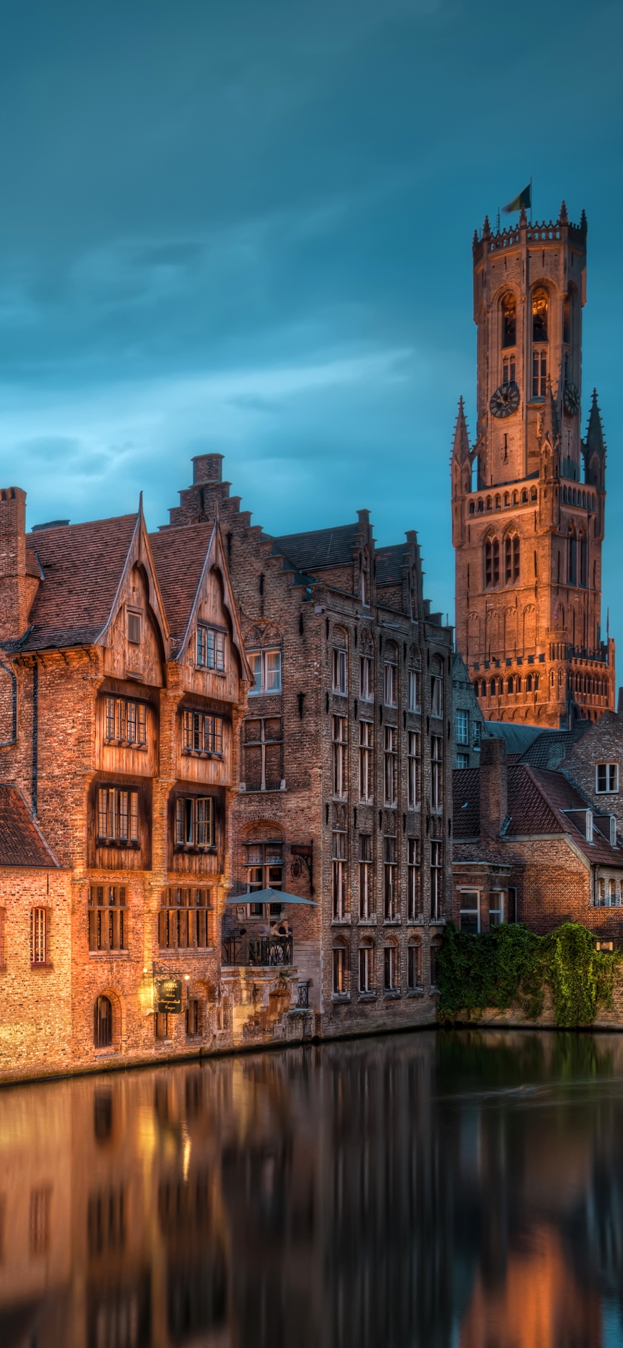 Edificio de Hormigón Marrón Cerca Del Cuerpo de Agua Bajo un Cielo Azul Durante el Día. Wallpaper in 1242x2688 Resolution