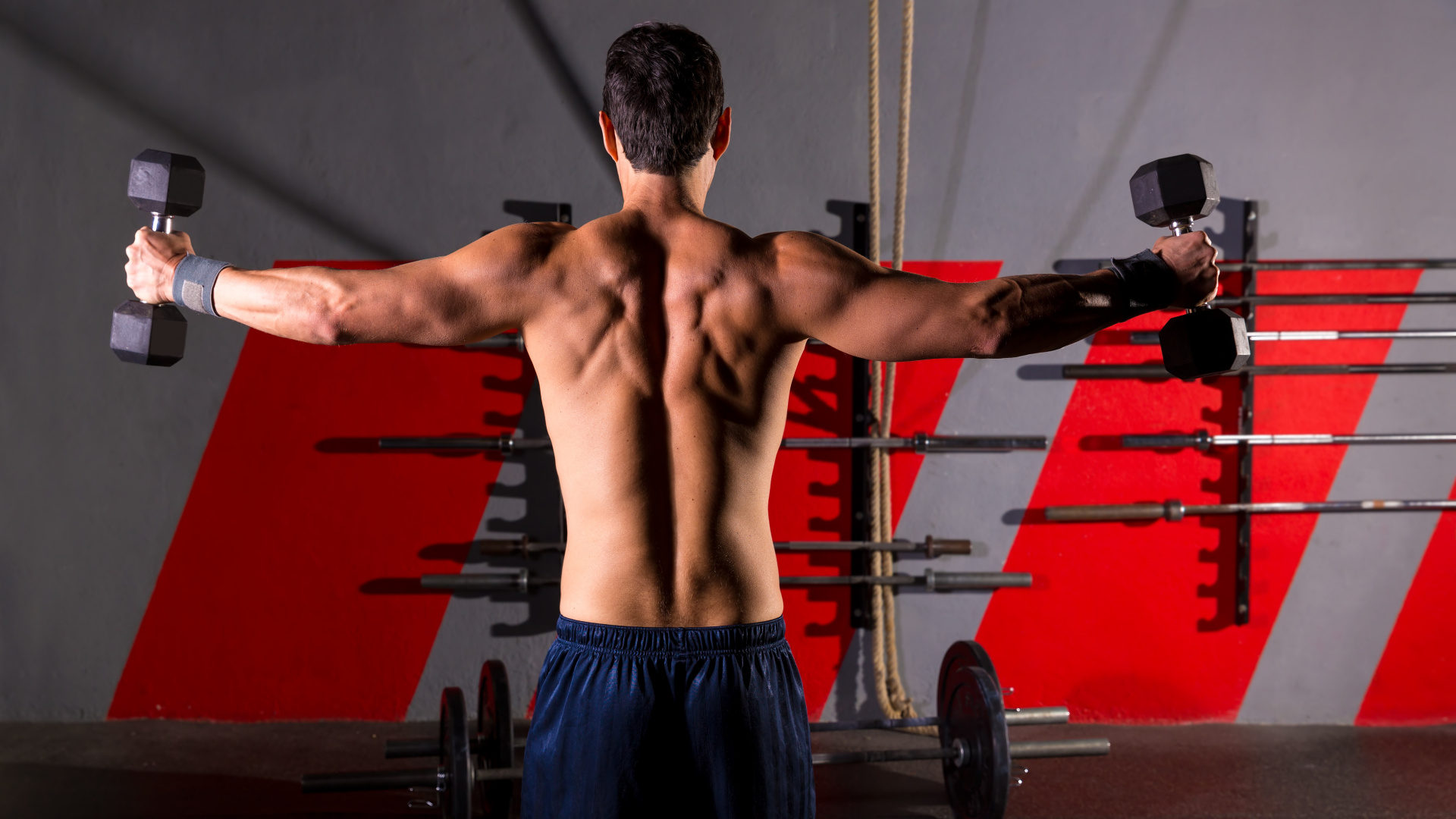 Man in Blue Shorts Standing Near Black and Red Exercise Equipment. Wallpaper in 1920x1080 Resolution