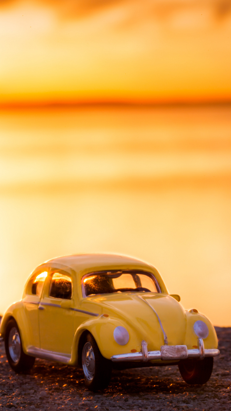 Volkswagen Beetle Jaune Sur le Rivage Pendant le Coucher du Soleil. Wallpaper in 750x1334 Resolution