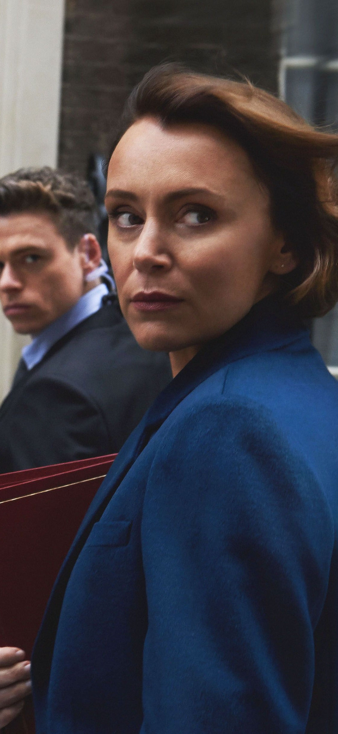 Man in Blue Sweater Standing Beside Woman in Black Coat. Wallpaper in 1125x2436 Resolution