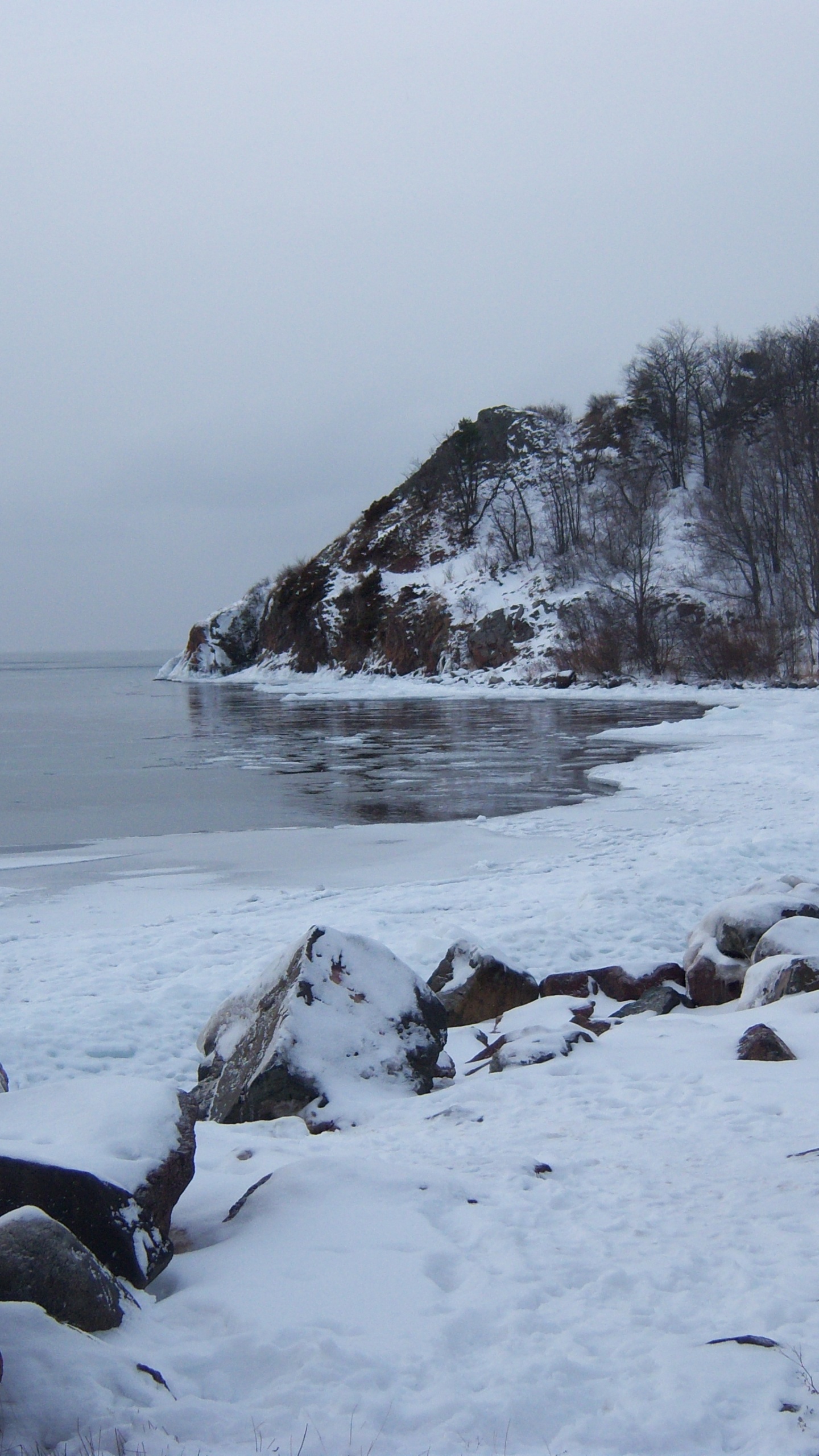 Snow Covered Rocks by The Sea During Daytime. Wallpaper in 1440x2560 Resolution