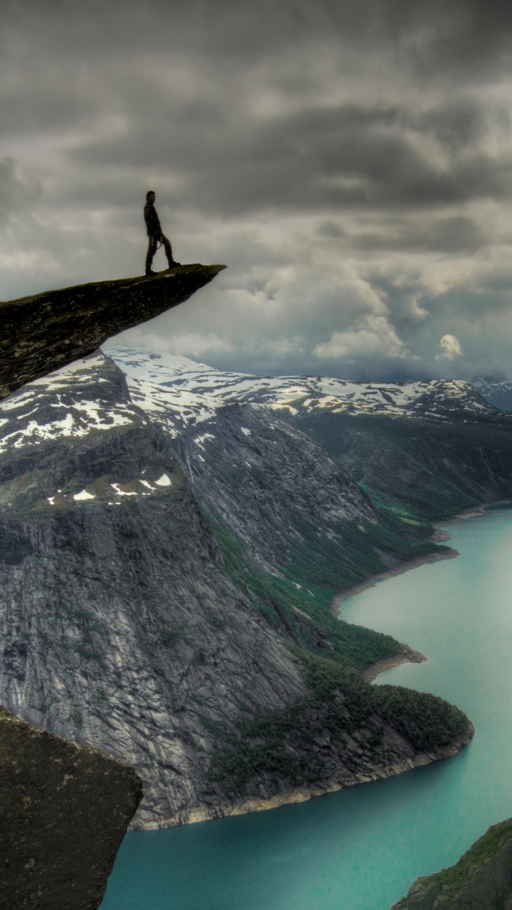 Person Standing on Rock Formation Near Lake Under Cloudy Sky During Daytime. Wallpaper in 720x1280 Resolution