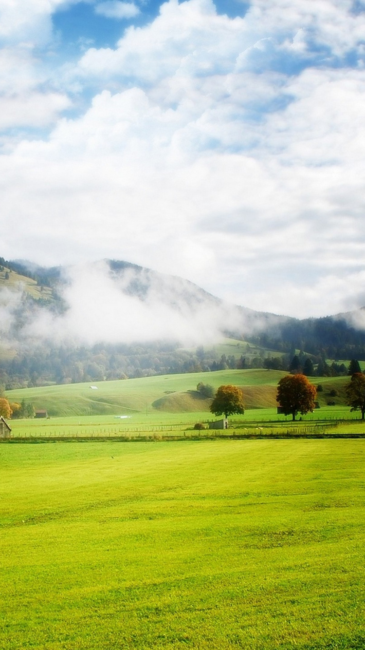 Champ D'herbe Verte Près de la Montagne Sous Des Nuages Blancs Pendant la Journée. Wallpaper in 750x1334 Resolution