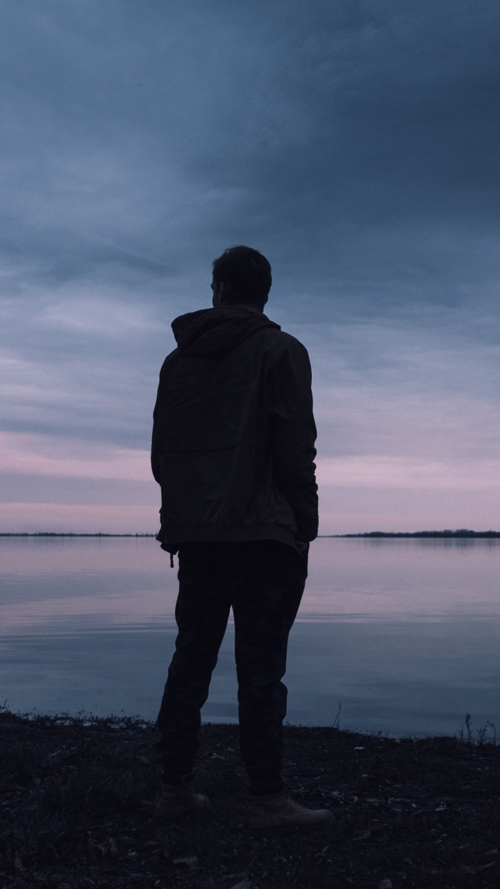Man in Black Jacket Standing Near Body of Water During Daytime. Wallpaper in 720x1280 Resolution