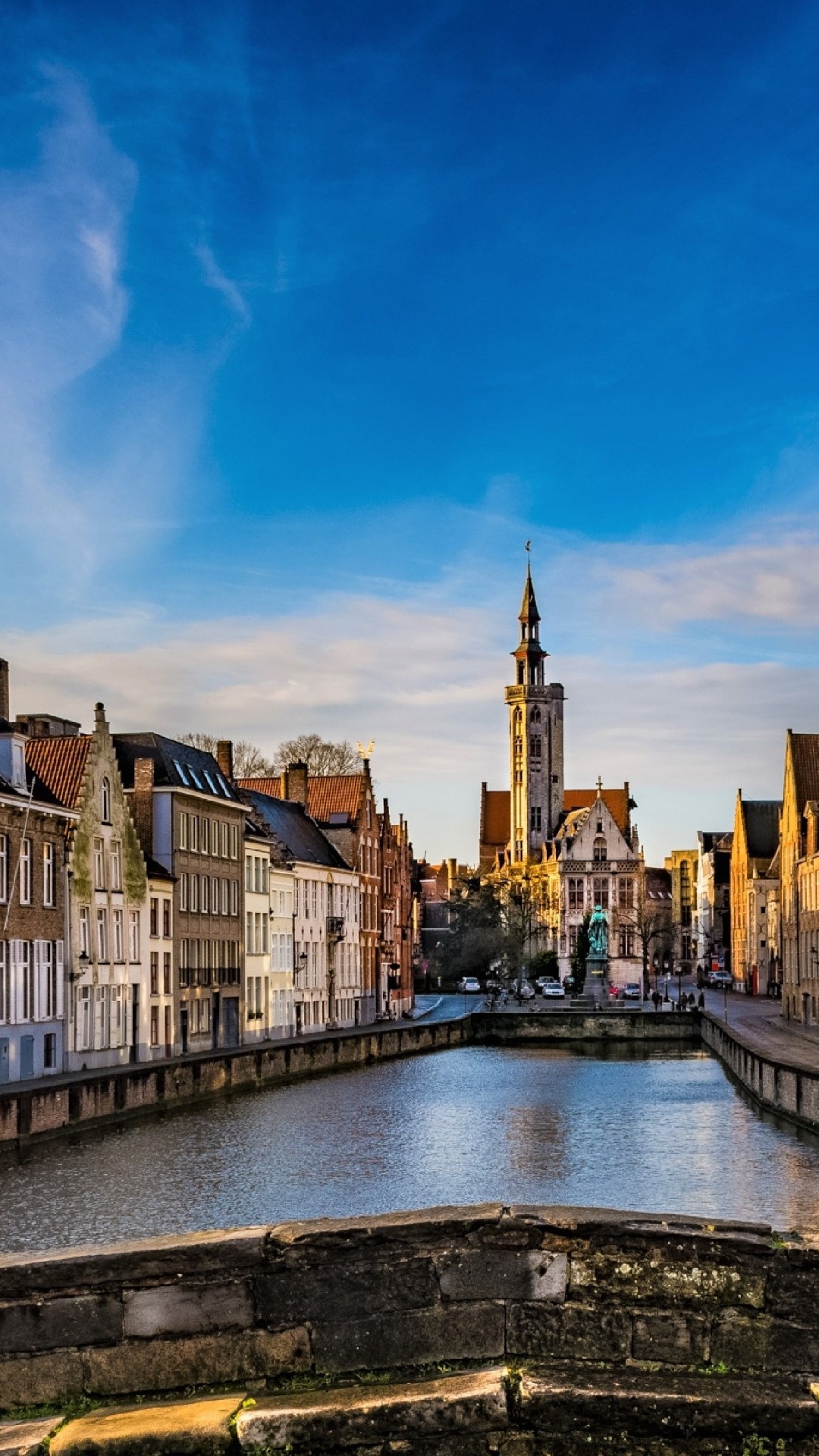 Brown and White Concrete Buildings Beside River Under Blue Sky During Daytime. Wallpaper in 1080x1920 Resolution