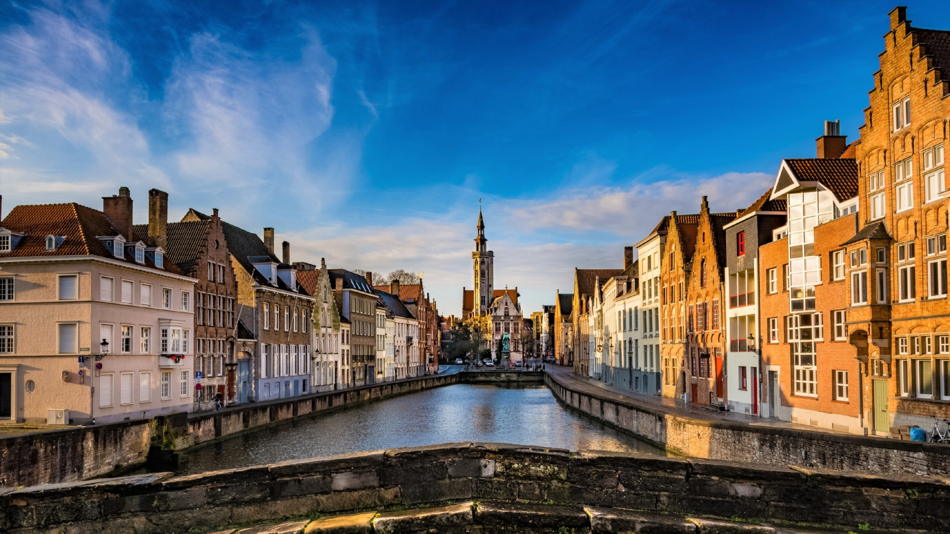Brown and White Concrete Buildings Beside River Under Blue Sky During Daytime. Wallpaper in 1920x1080 Resolution