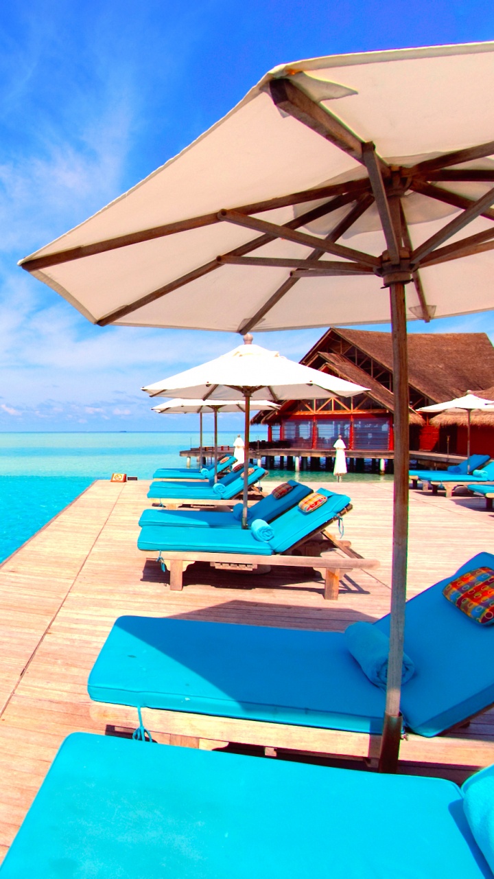 White and Brown Wooden Beach Lounge Chairs on Blue Sea Under Blue Sky During Daytime. Wallpaper in 720x1280 Resolution