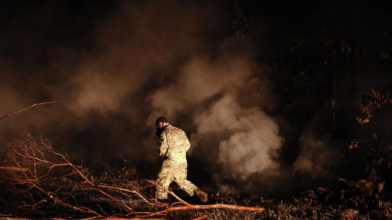 Hombre de Chaqueta y Pantalón Negro Sentado Sobre Una Roca Marrón. Wallpaper in 1366x768 Resolution