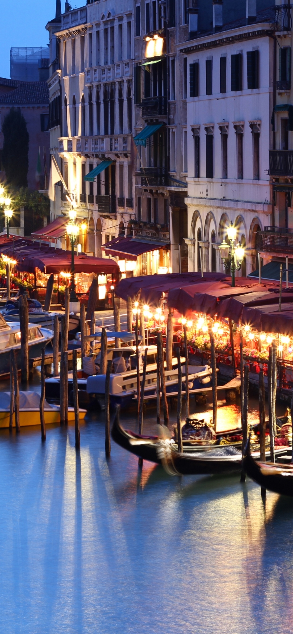 People Riding on Boat on River Near Buildings During Night Time. Wallpaper in 1242x2688 Resolution