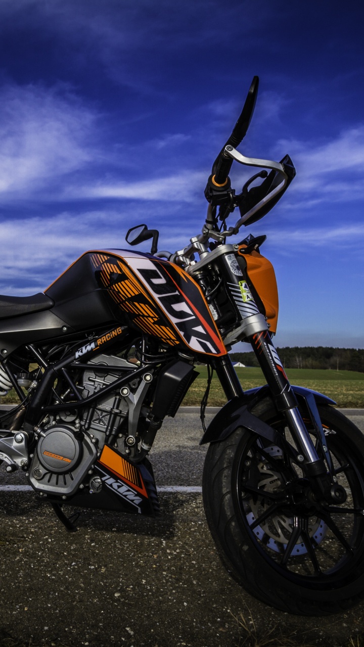 Orange and Black Motorcycle on Black Asphalt Road Under Gray Cloudy Sky. Wallpaper in 720x1280 Resolution