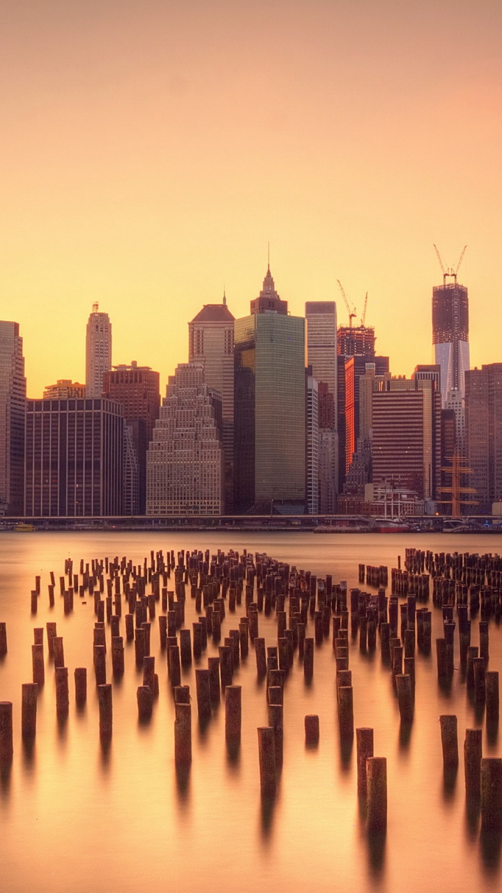 City Skyline Across Body of Water During Sunset. Wallpaper in 720x1280 Resolution