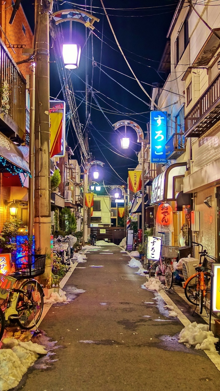 Rue Vide Avec Des Voitures Garées à Côté Des Bâtiments Pendant la Nuit. Wallpaper in 720x1280 Resolution