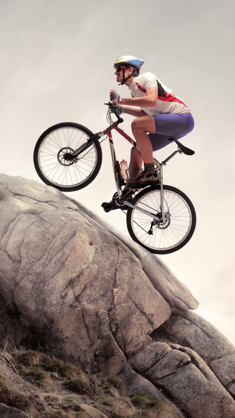 Man in White Shirt and Black Shorts Riding on Black Mountain Bike on Brown Rock Mountain. Wallpaper in 750x1334 Resolution