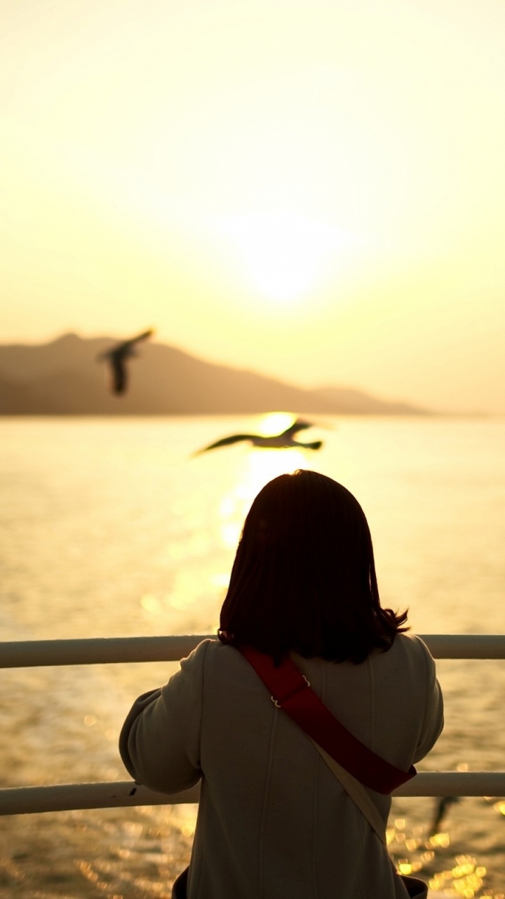 Femme en Chemise Blanche à Manches Longues Debout Sur la Plage Pendant le Coucher du Soleil. Wallpaper in 720x1280 Resolution