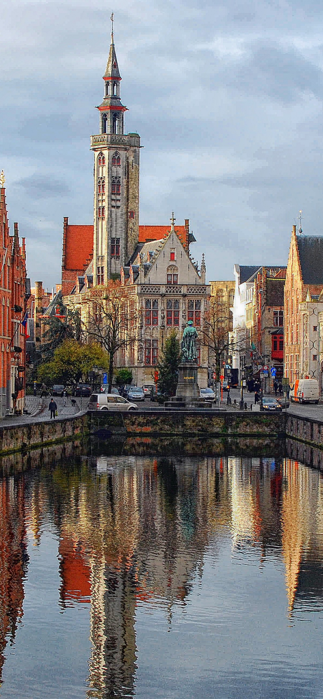 Brown and White Concrete Buildings Beside River Under White Clouds During Daytime. Wallpaper in 1125x2436 Resolution