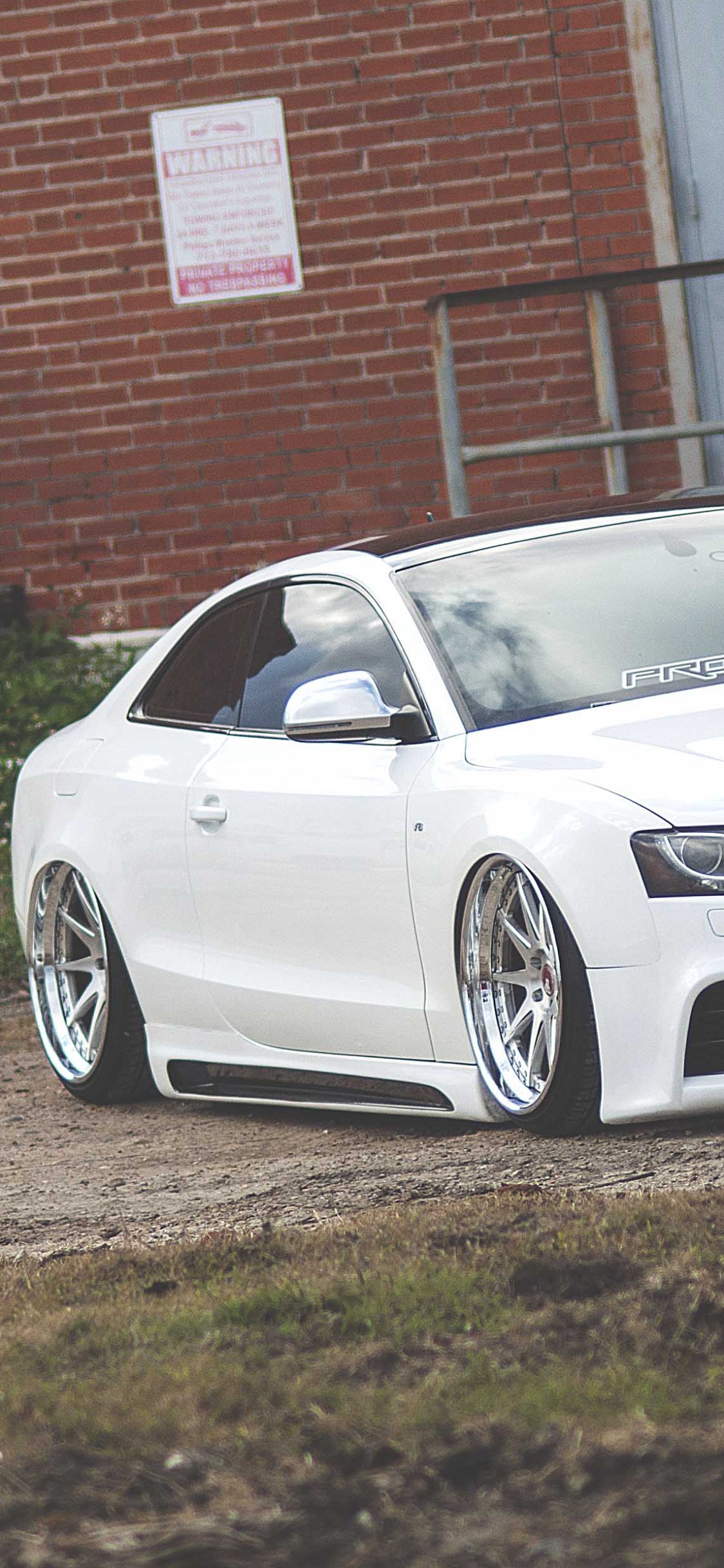 Audi r 8 Blanche Garée Près D'un Immeuble en Briques Brunes. Wallpaper in 1125x2436 Resolution