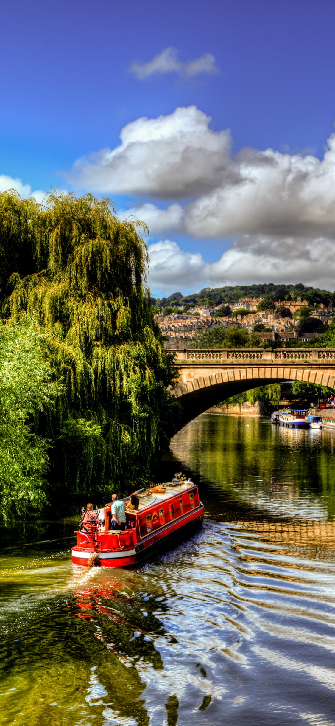 Barco Rojo en el Río Cerca de Árboles Verdes Bajo un Cielo Azul y Nubes Blancas Durante el Día. Wallpaper in 1125x2436 Resolution