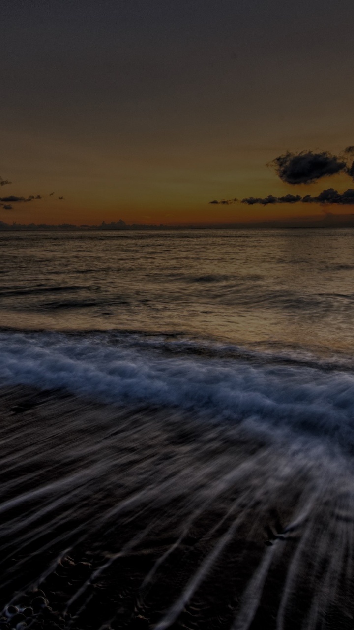 Olas Del Océano Rompiendo en la Orilla Durante la Puesta de Sol. Wallpaper in 720x1280 Resolution