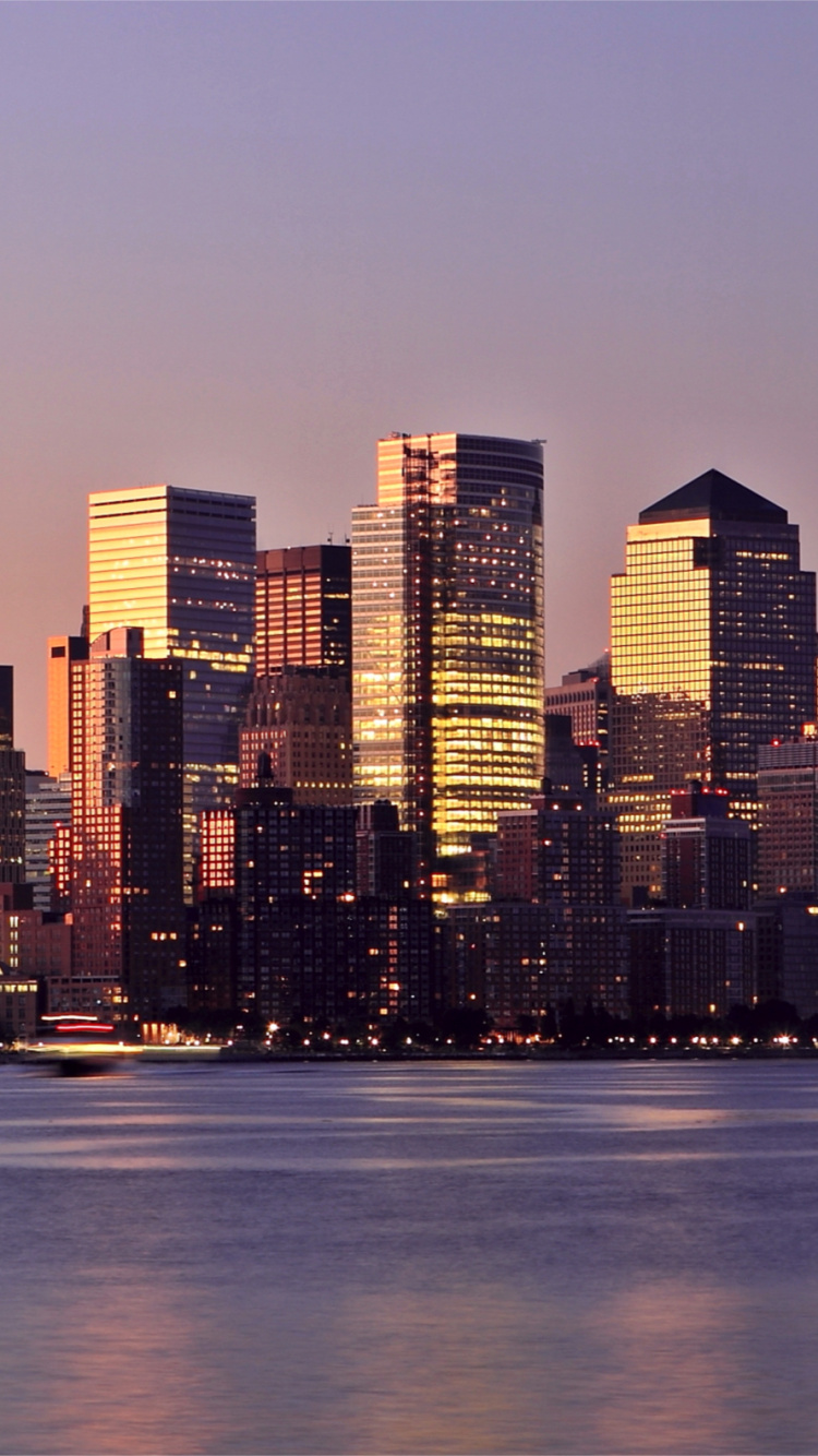 Skyline Der Stadt Über Gewässer Während Der Nacht. Wallpaper in 750x1334 Resolution