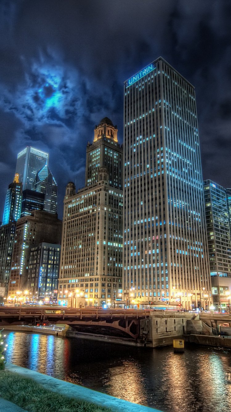 Skyline Der Stadt Über Gewässer Während Der Nacht. Wallpaper in 750x1334 Resolution