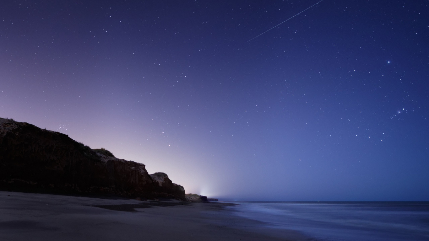 Brown Rock Formation Near Body of Water During Night Time. Wallpaper in 1366x768 Resolution