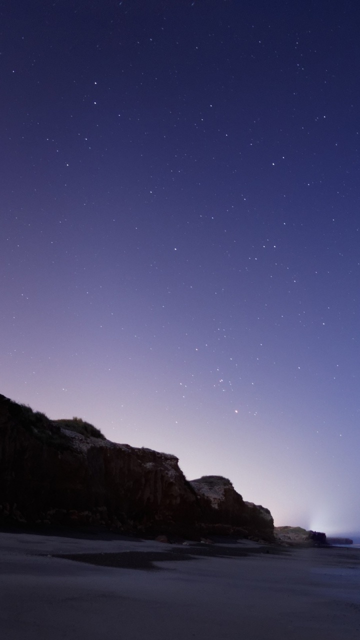 Brown Rock Formation Near Body of Water During Night Time. Wallpaper in 720x1280 Resolution
