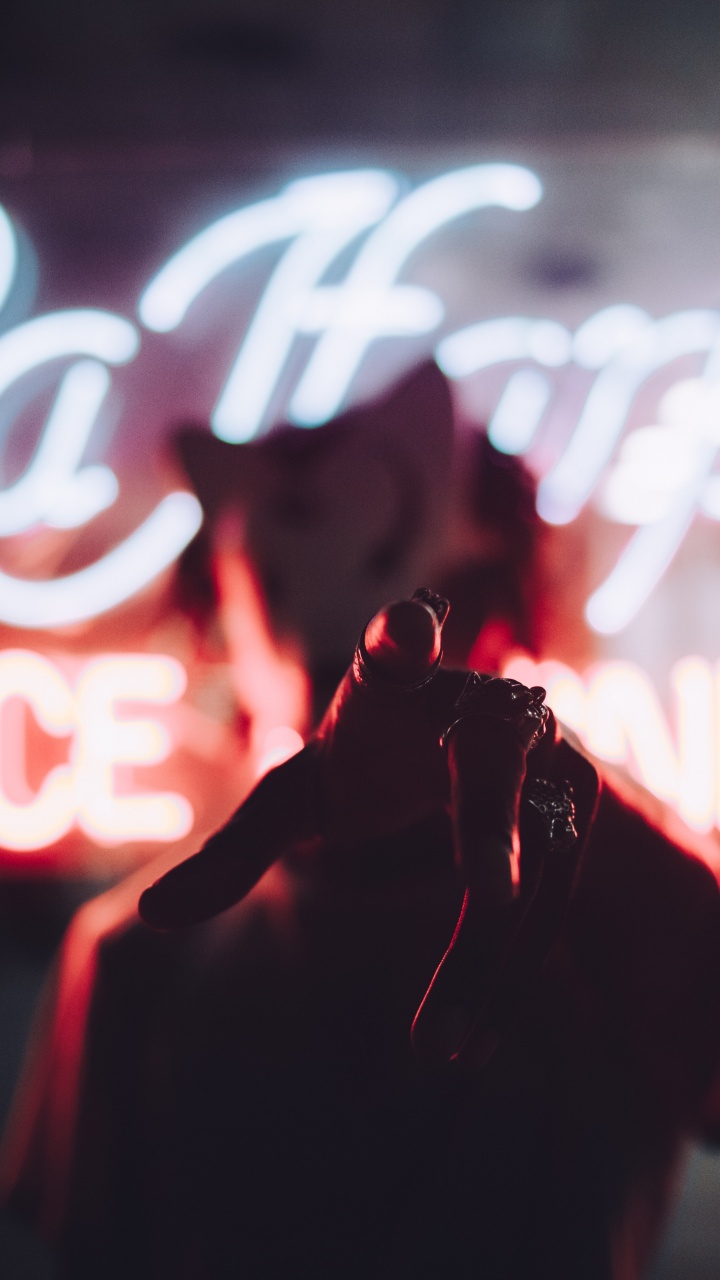 Person in Red Jacket Standing in Front of Red and White Neon Light Signage. Wallpaper in 720x1280 Resolution