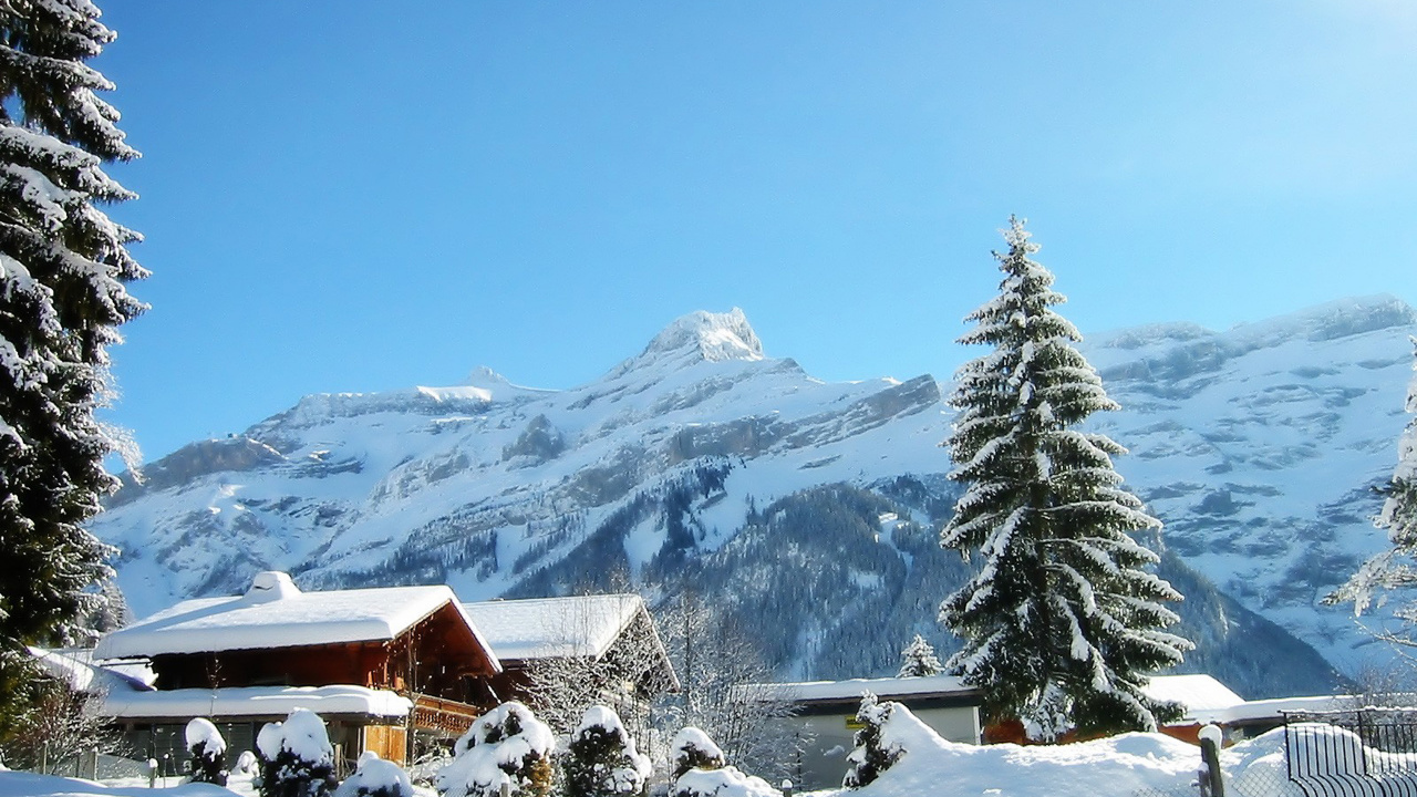 Maison en Bois Brune Sur un Sol Couvert de Neige Près de Pins Verts et de Montagnes Couvertes de Neige Pendant. Wallpaper in 1280x720 Resolution