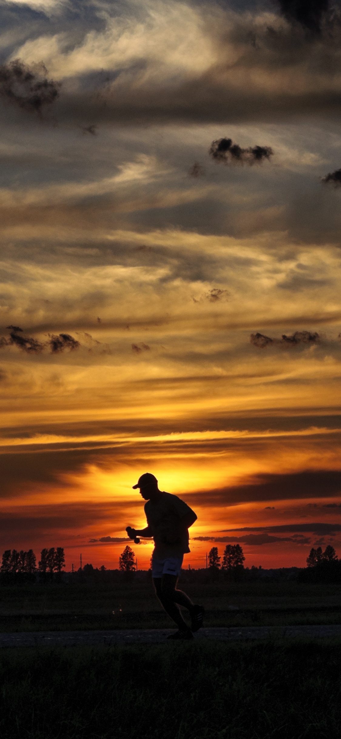 Silhouette D'homme Marchant Sur Terrain en Herbe Pendant le Coucher du Soleil. Wallpaper in 1125x2436 Resolution