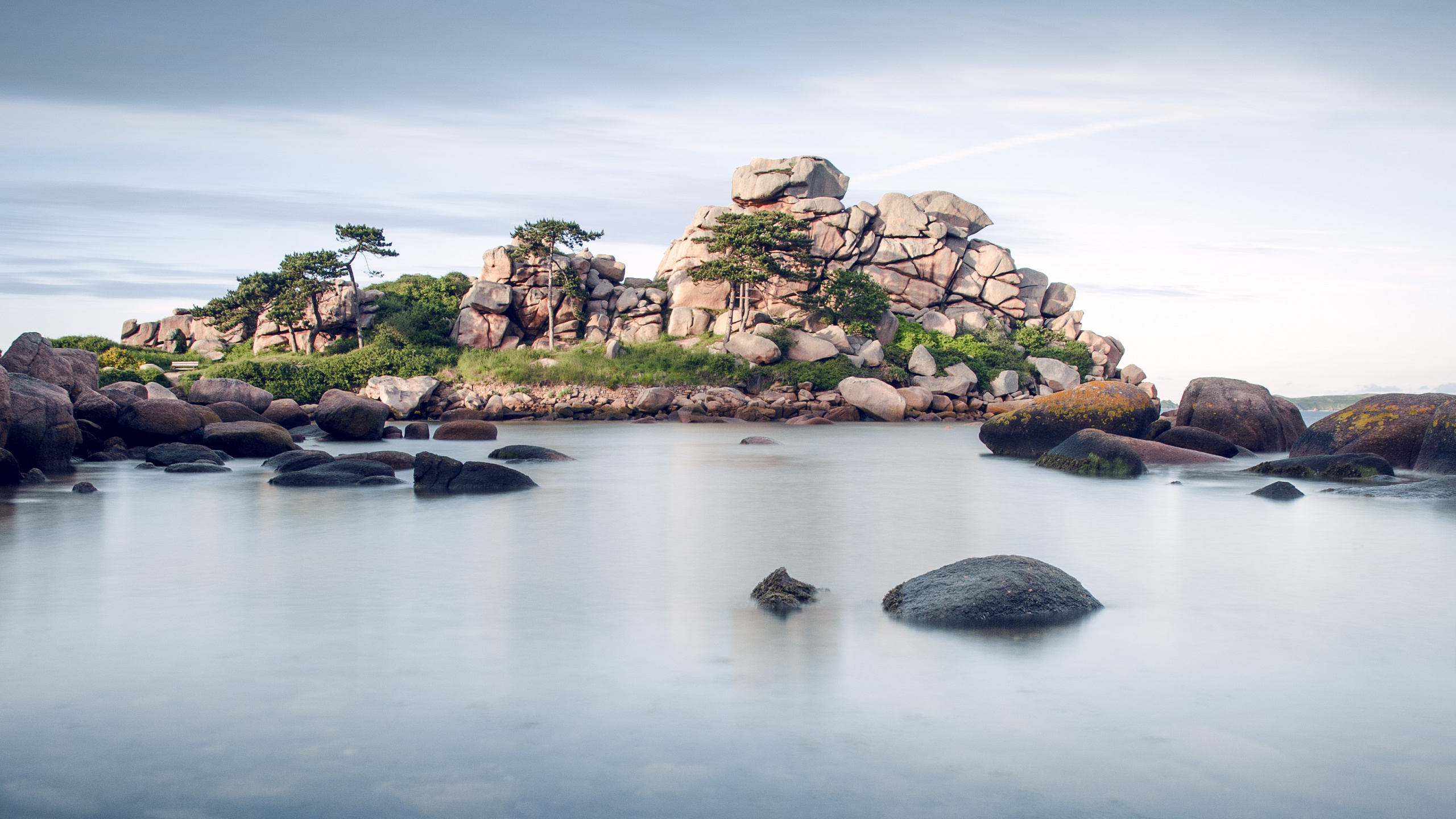 Green and Brown Rock Formation on Body of Water Under Blue Sky During Daytime. Wallpaper in 2560x1440 Resolution