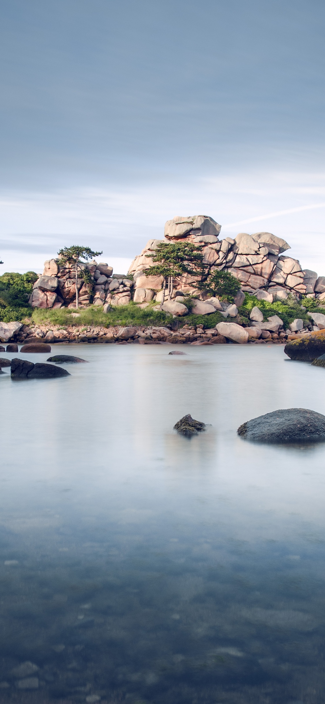 Formation Rocheuse Verte et Brune Sur un Plan D'eau Sous un Ciel Bleu Pendant la Journée. Wallpaper in 1125x2436 Resolution