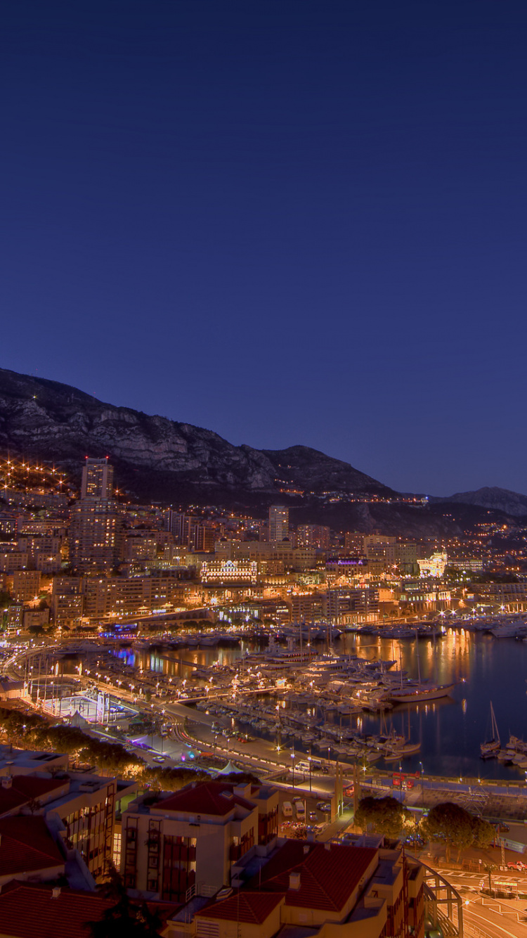 Ville Avec Des Immeubles de Grande Hauteur Près de la Montagne Pendant la Nuit. Wallpaper in 750x1334 Resolution