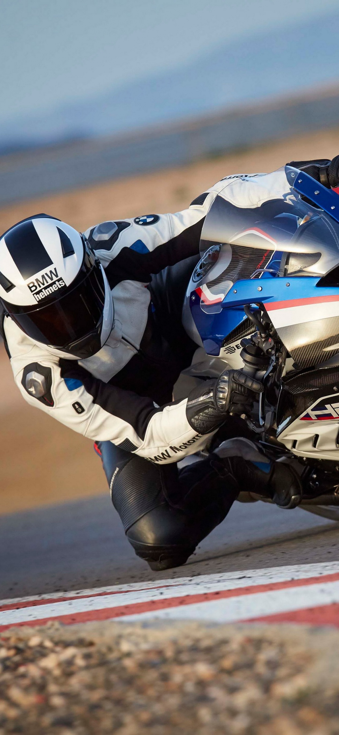 Homme en Costume de Moto Noir et Blanc à Cheval Sur un Vélo de Sport. Wallpaper in 1125x2436 Resolution