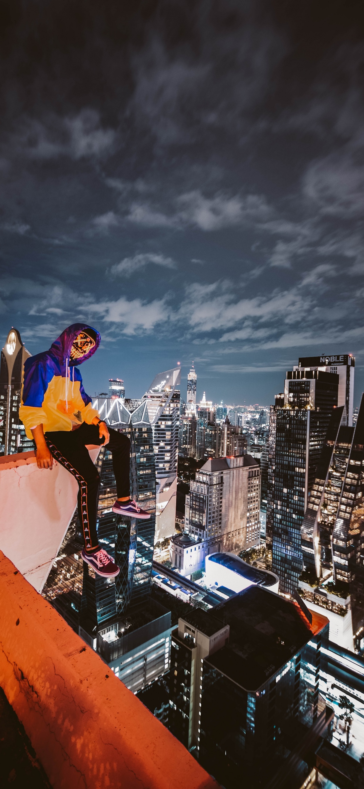 Man in Blue Long Sleeve Shirt and Black Pants Standing on Top of Building During Night. Wallpaper in 1242x2688 Resolution