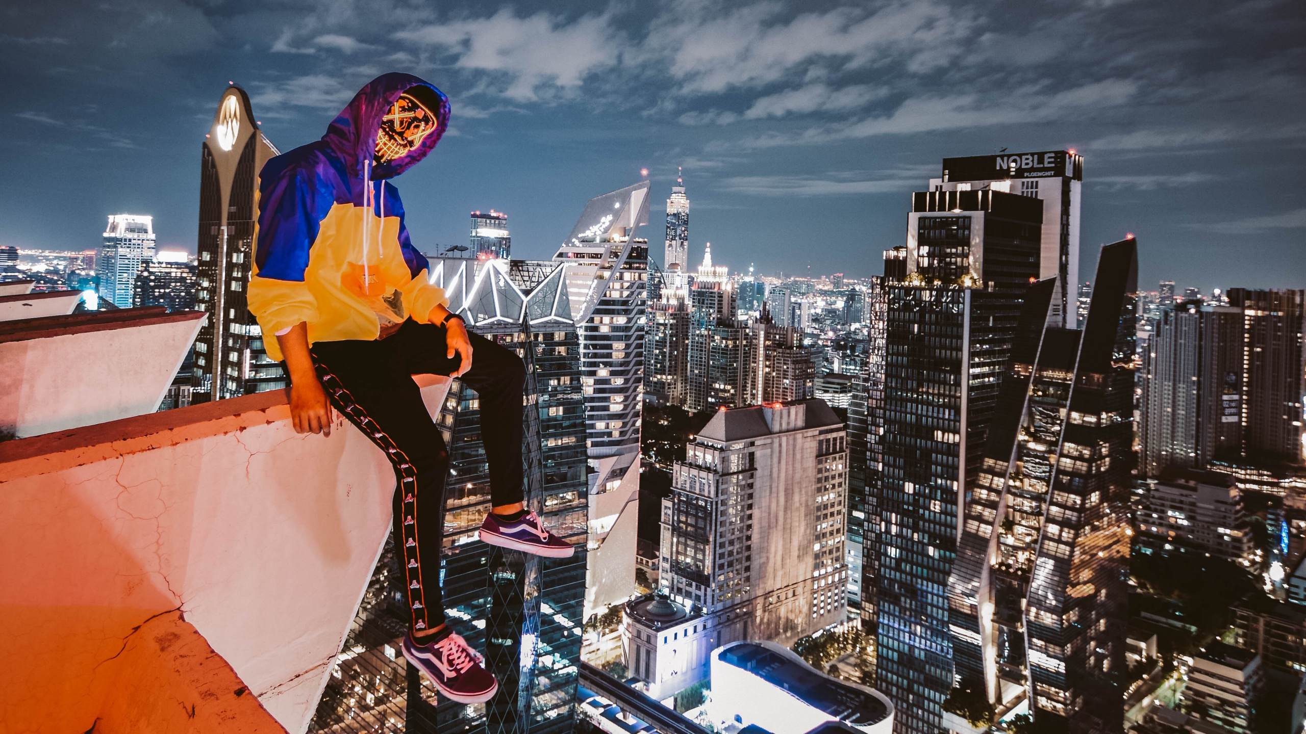 Man in Blue Long Sleeve Shirt and Black Pants Standing on Top of Building During Night. Wallpaper in 2560x1440 Resolution